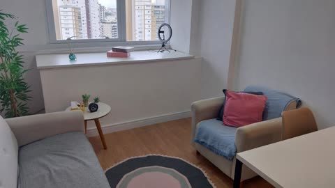Sala de atendimento com poltronas, planta e janela com vista para a cidade — Consultório rosa