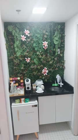 Copa com cafeteira, geladeira e parede decorada com plantas