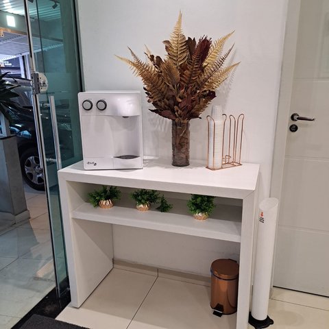 Aparador com purificador de água, vaso decorativo e copos descartáveis