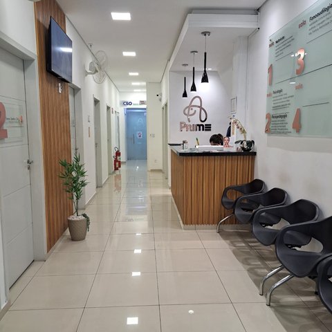 Corredor com poltronas de espera e balcão de recepção do prédio