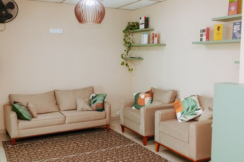 Sala de espera com dois sofás, poltronas e estantes com livros