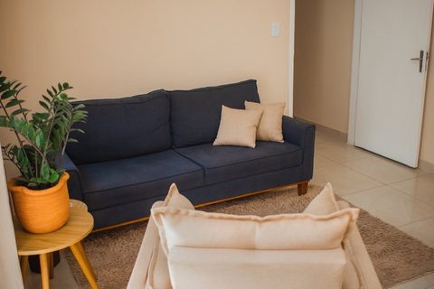 Sofá azul-marinho, outro ângulo, com planta e porta ao fundo — Consultório 02
